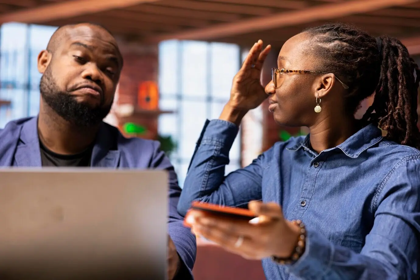 Afroamerikanische Frau, die ihren Freund wegen seiner Geldausgaben zur Rede stellt.